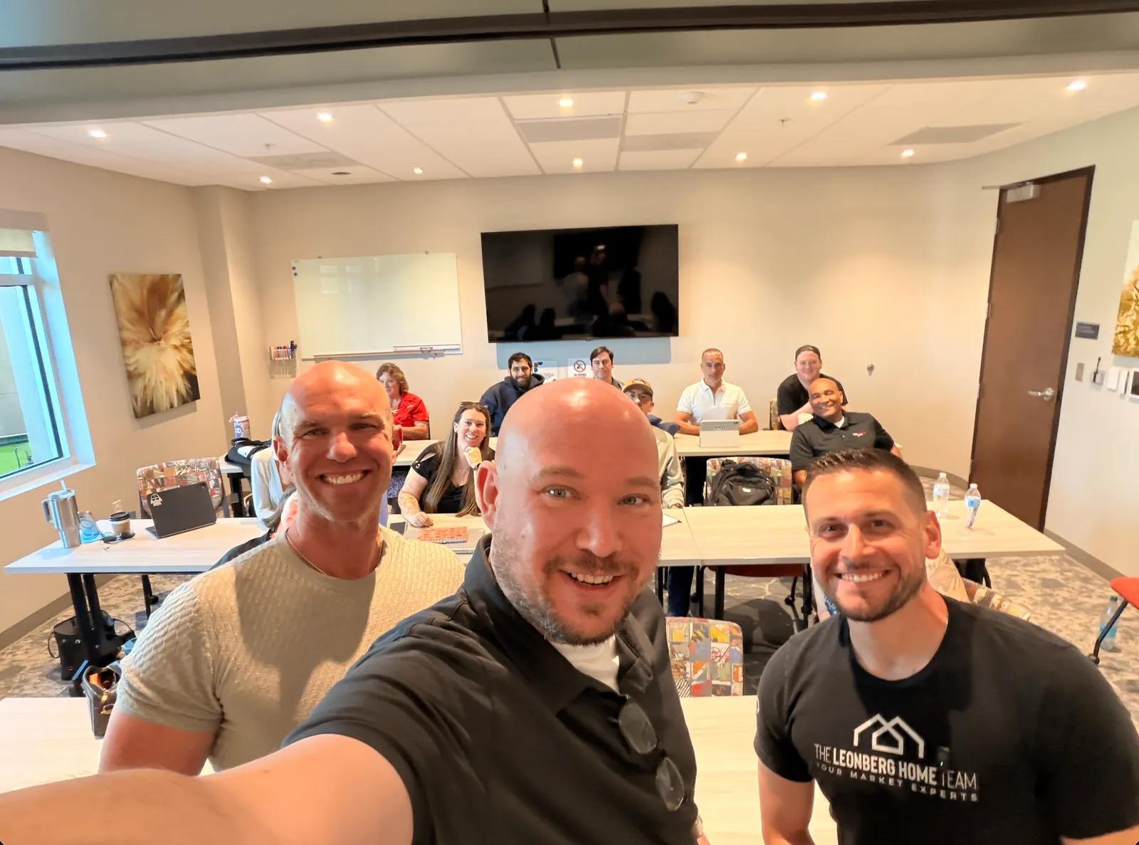 Chad Leonberg with two agents at a team training session, with a group at tables behind them
